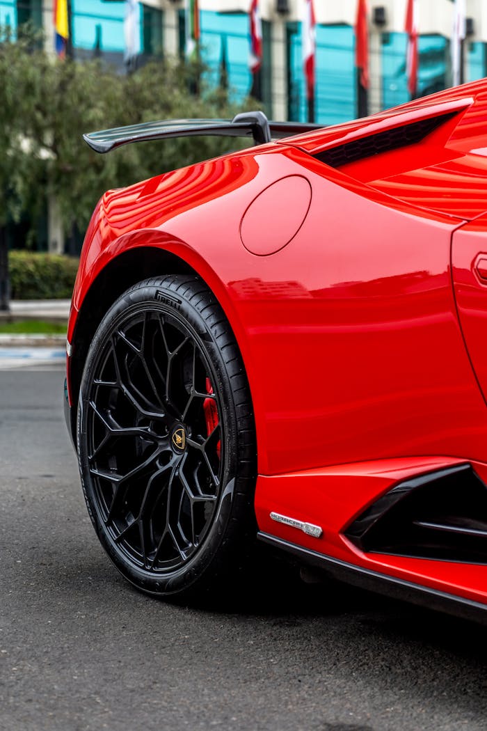 Close-up of a red sports car with stylish wheels, captured outdoors.